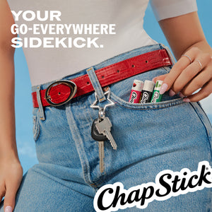 Lip balm sticks tucked into a jeans pocket, held by a hand beside keys